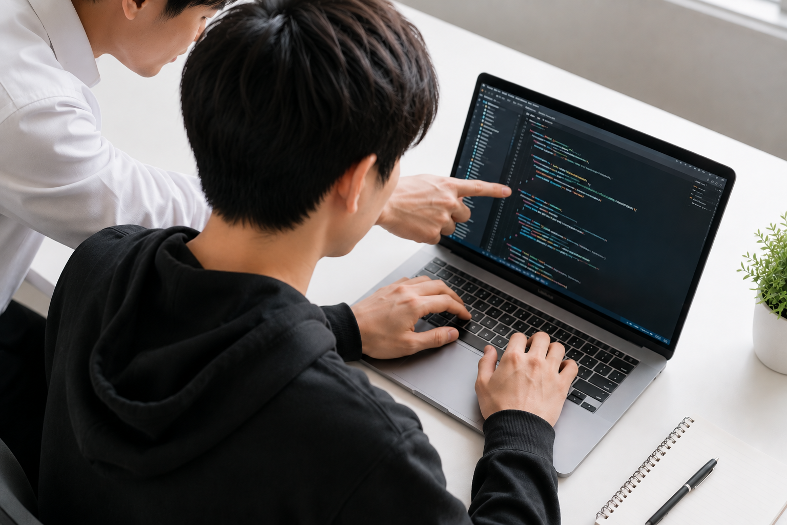 講師が受講者のパソコン画面を見ながらプログラミングを指導する様子